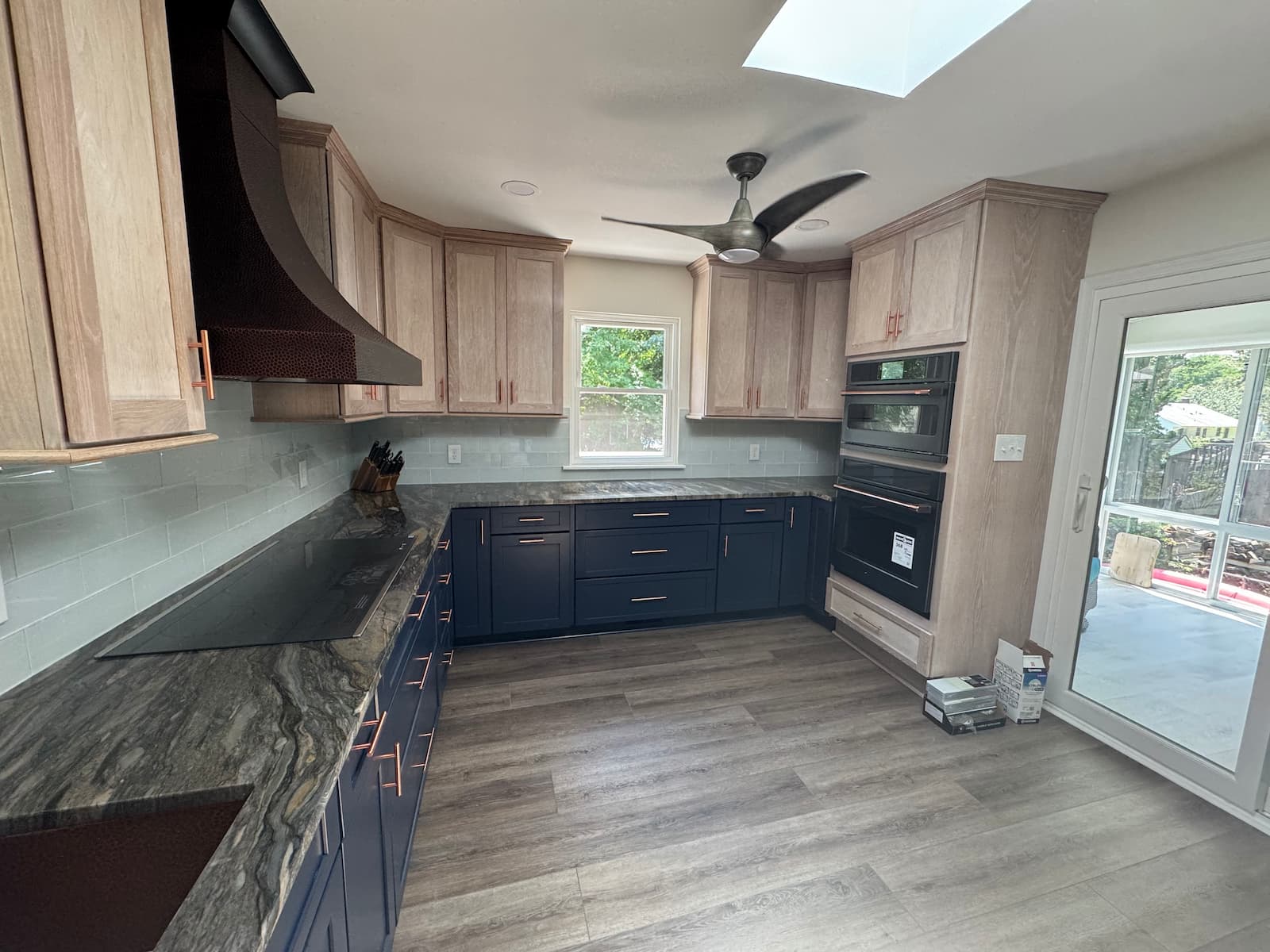 Updated kitchen with navy base cabinets, light wood uppers, stone countertops, and modern appliances installed by Blue Horizon Renovations.