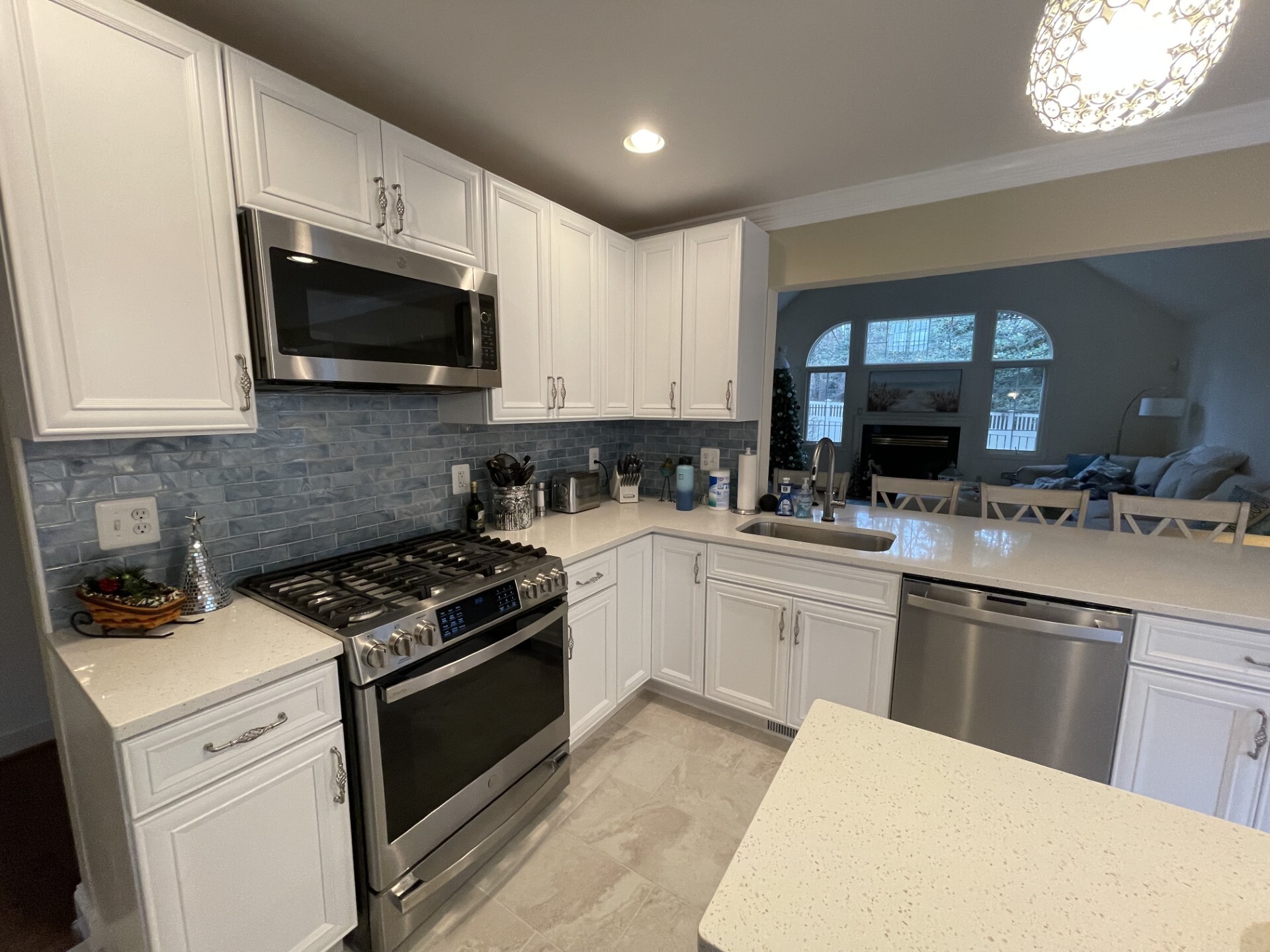 Remodeled kitchen with white cabinetry, stainless steel appliances, quartz countertops, and blue tile backsplash completed by Blue Horizon Renovations.